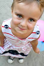Adorable little girl playing with balloons looking up