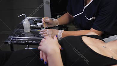 A close-up cosmetologist applies anesthesia to the lips before permanent makeup.