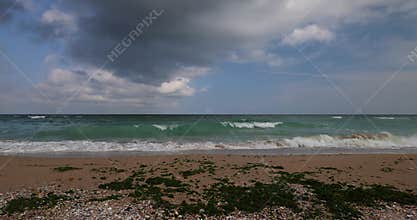 Deserted autumn beach. Calm sea waves rolling on empty sea beach at cold cloudy day.