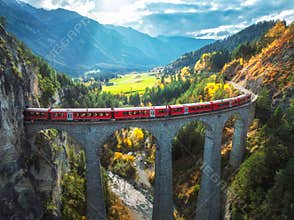 Aerial view of red train on Landwasser viaduct in autumn in Alps