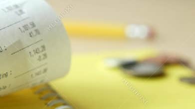 A receipt, coins, and a pencil on a table symbolize finance, transactions, and commerce