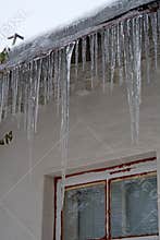 Large long icicles hang from roof of house
