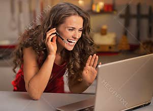 Happy woman having video chat on laptop in kitchen