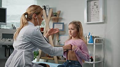 Paediatrician listening girl lungs in examination room. Cute child breathing