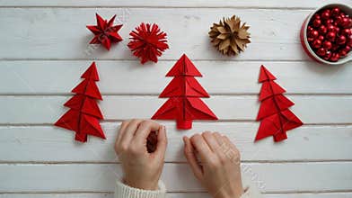Woman creating red origami christmas trees for holiday decorations