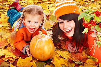 Happy family with pumpkin on autumn leaves.