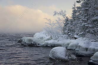 The icy coast of the island Valaam and fog over the black lake Ladoga