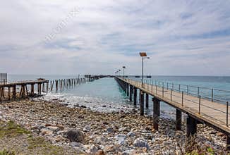 An abandoned commercial jetty and a new fishing jetty in aquamarine waters.