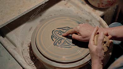 Artisan makes beautiful handcrafted on spinning pottery wheel in workshop. Professional ceramics artist painting on clay