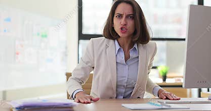 Young business woman director in office swears screams, bangs hands on table in office
