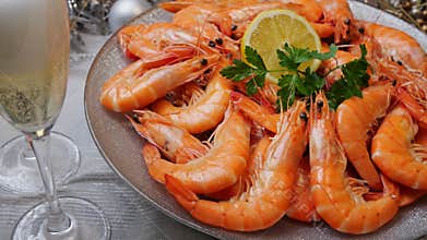 Boiled shrimps on a plate rotating, Christmas New Year decoration, pour champagne into a glass. Close up