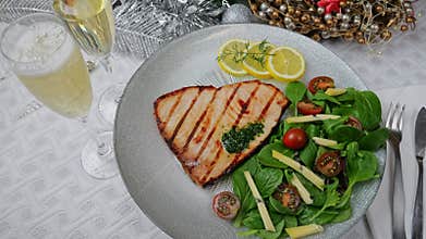 Grilled swordfish steak with fresh salad, tomatoes and cheese on a plate rotating. Christmas New Year decoration.