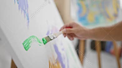 Handsome young hispanic man, an aspiring artist, passionately drawing in the heart of his art studio, carefully holding his