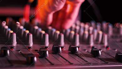 Hand Settings Volume Level Controls on Mixing Console Faders Neon Light Close-Up