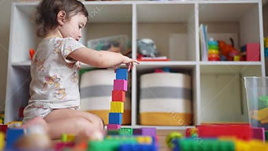 baby plays with toy blocks on the floor. development of fine motor skills in lifestyle children concept. baby daughter