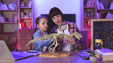 Caucasian mother with daughter examine skeleton of dinosaur.