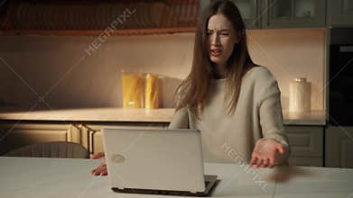 Young Woman Expressing Confusion at Laptop Screen in Modern Kitchen
