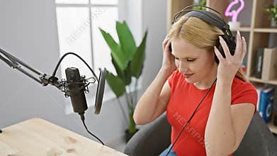 Young blonde woman in red shirt podcasting in a modern studio with a microphone and headphones