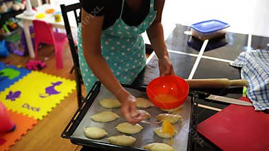 Housewife smears buns on a baking sheet with beaten egg