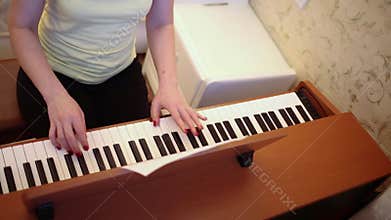 Young woman is playing on a wooden piano, top