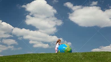 small girl rolling inflatable globe looking ball