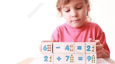 girl play wooden blocks with numbers, builds wall