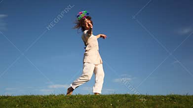 pretty young woman runs and turns on grass holding