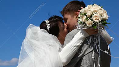 hugging bride and bridegroom kissing outdoor, blue