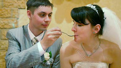 bridegroom feeding bride sits at wedding