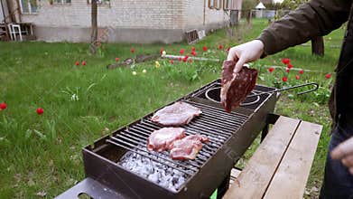 A young man puts a steak on the grill.