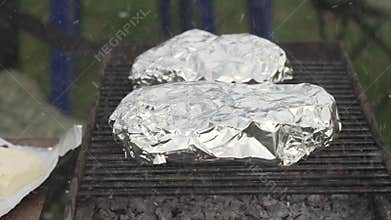 Ashes from a burning fire in a grill on which steaks are cooked.