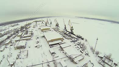 Empty cargo dock with cranes near hangars on shore