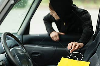 Thief stealing shopping bag from the car
