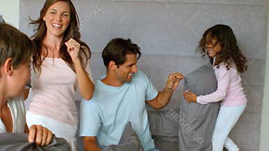 Smiling family having a pillow fight