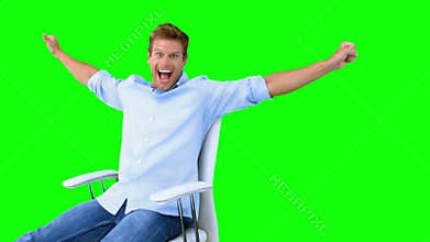 Man sitting on swivel chair with raised arms to show his success on green screen