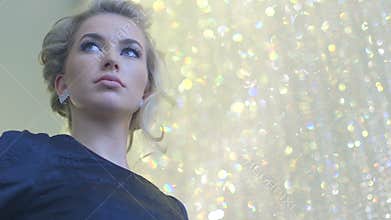 Attractive blonde woman with diamond earrings and black evening dress waiting for somebody