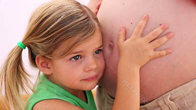 Little girl listening to mothers pregnant belly