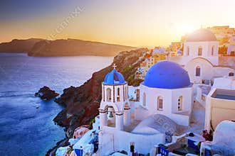Oia town on Santorini island, Greece at sunset. Rocks on Aegean sea.