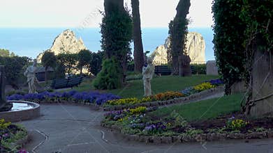 View of the Faraglioni from the Gardens of Augustus in Capri, Italy with flowers and statues