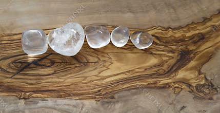 Clear quartz crystals on olive wood background