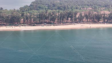 Aerial view of the beautiful Querim Beach in Goa, India, featuring a sandy shore lined with a distinctive row of tall casuarina