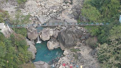 Aerial view of the famous Blue Lagoon natural pool in Meghalaya, India, with tourists swimming in turquoise water and crossing a