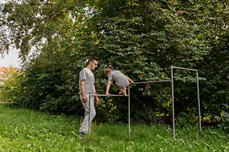 A father encourages his child as they play at a local playground filled with vibrant nature. They bond through laughter and joy on
