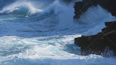 Surf crashing into black lava cliffs