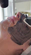 Young woman getting carbon laser facial at beauty clinic. Professional skincare