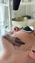 Young woman getting carbon laser facial at beauty clinic. Professional skincare