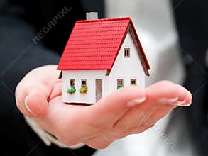 A real estate agent holding a small new house in her hands