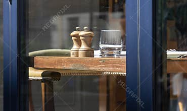 Rustic Wooden Table with Pepper Mills and Glass Seen Through Window