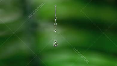 Drop of water falling against green natural background