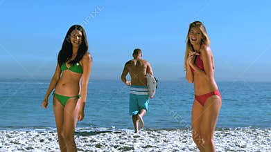 Pretty girls admiring a friend running toward the sea